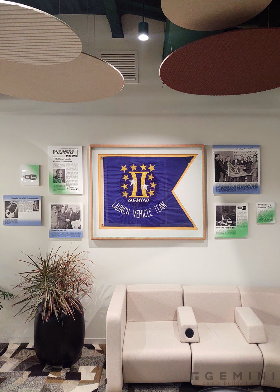 Littelfuse corporate history wall with the Gemini Launch Vehicle Team flag surrounded by floating historical acrylic panels.