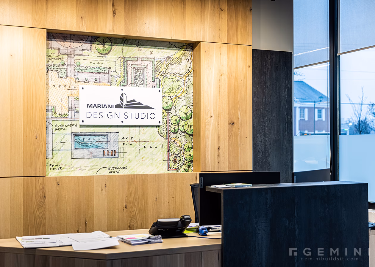 Custom Mariani Design Studio reception sign installed over a landscape design plan mural.
