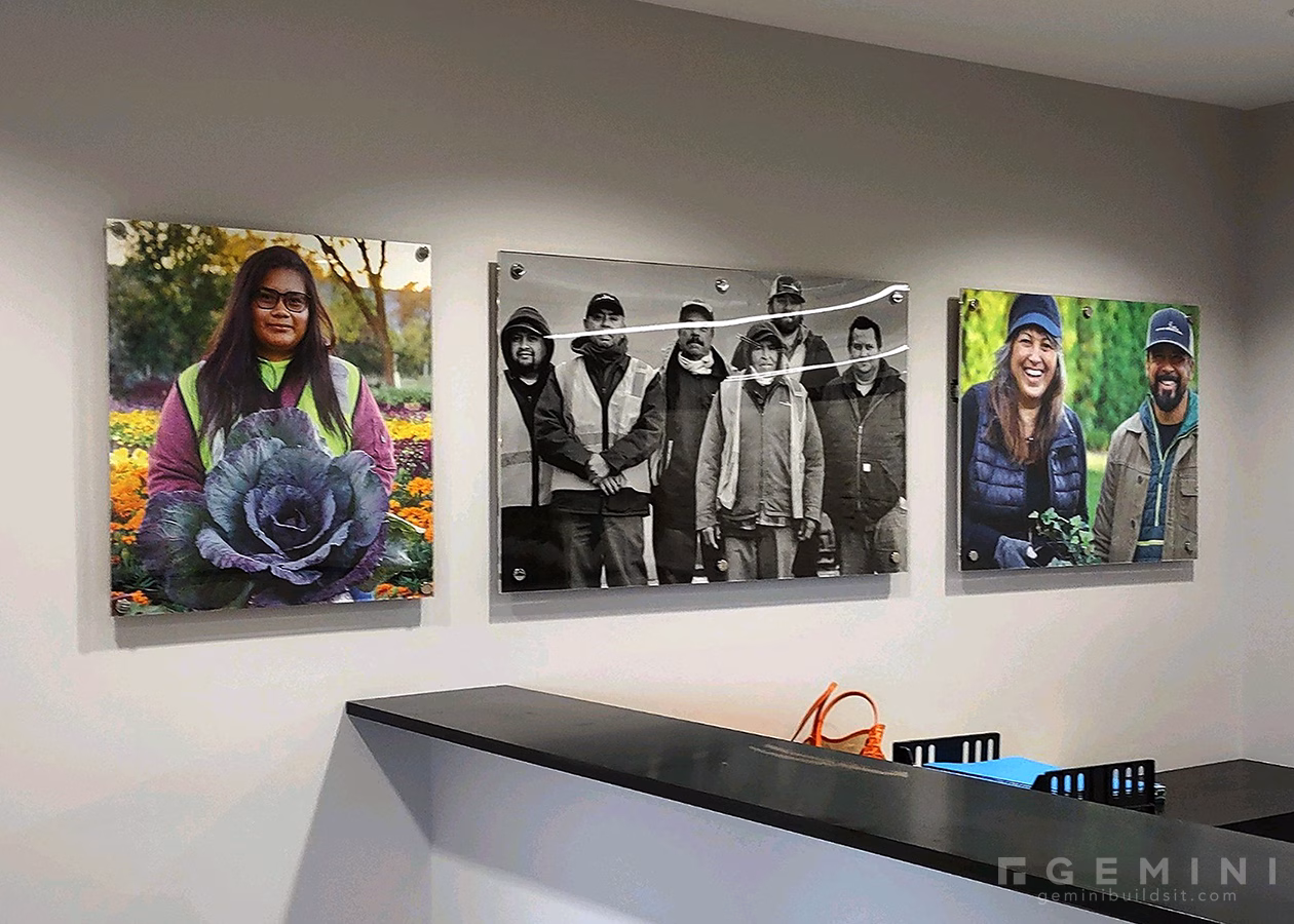 Custom office artwork including acrylic sandwich frames displaying Mariani employee photography with metal standoffs